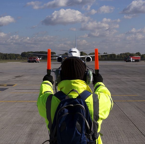 Ramp agent guiding aircraft on the tarmac, showcasing hands-on careers in aviation